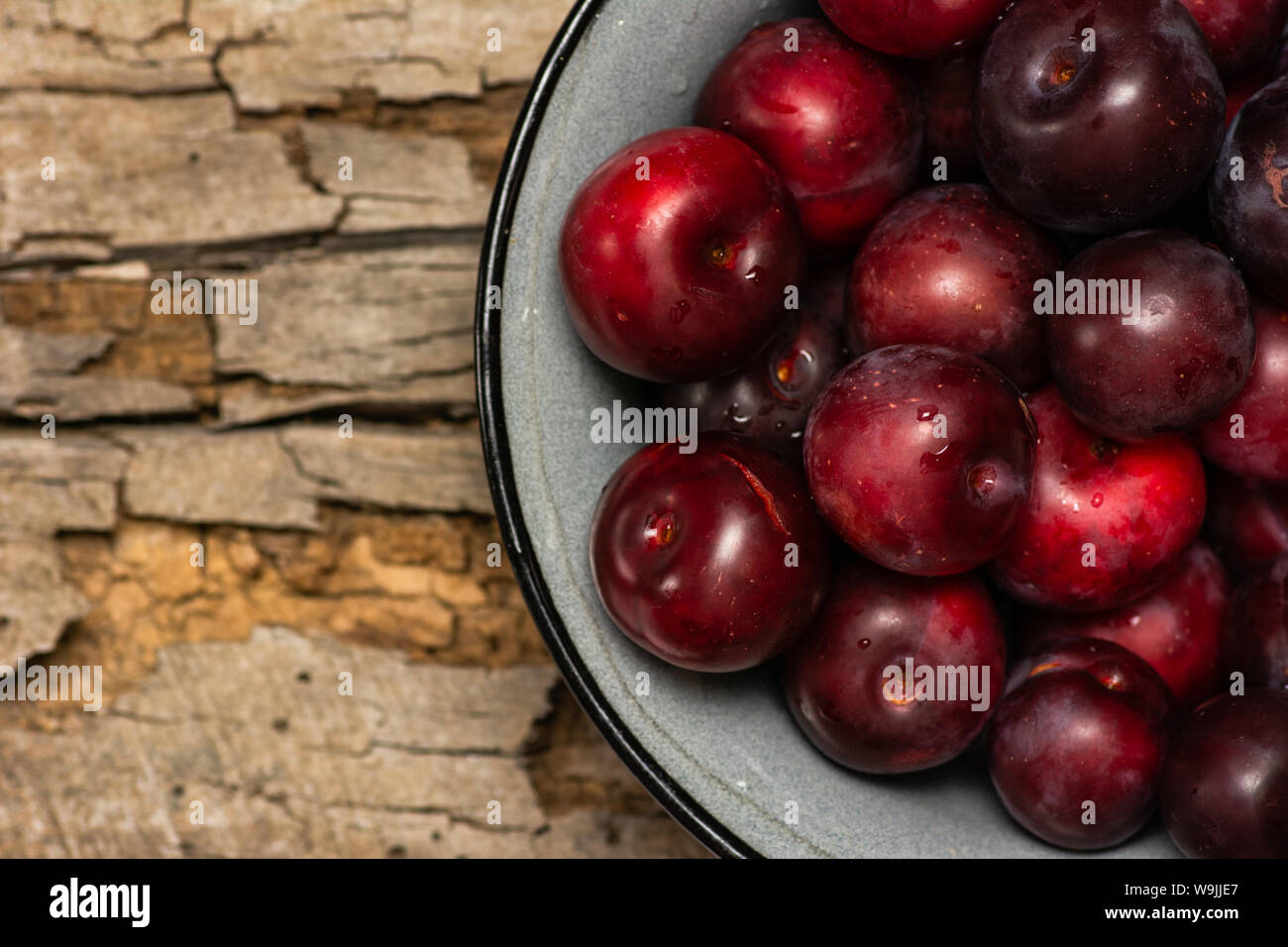 Libre de prunes fraîches rouge dans un bol sur une table en bois Banque D'Images