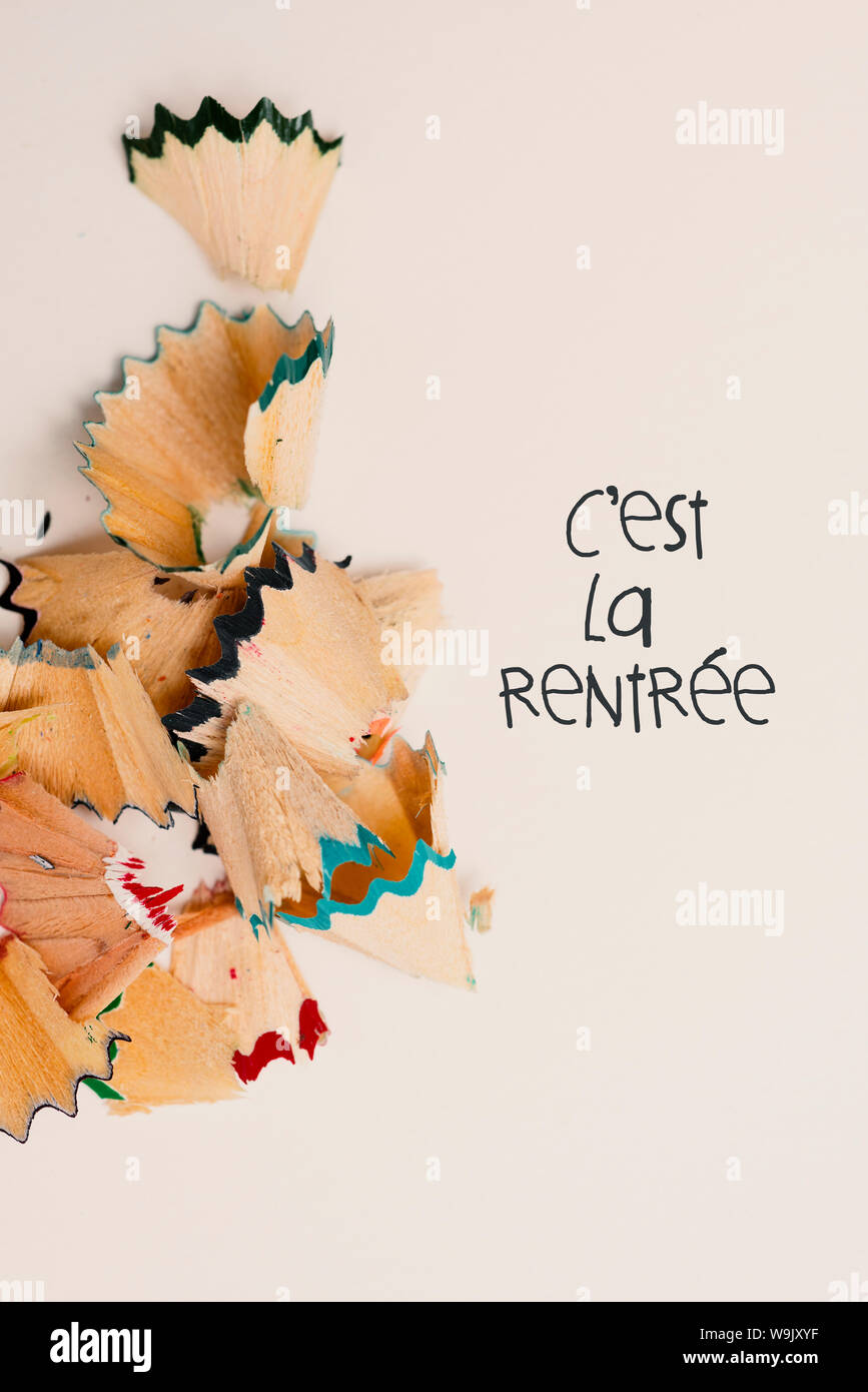 Certains ayant la forme de copeaux de crayons de couleurs différentes et le texte cest la rentrée, le retour à l'école écrit en français, sur une zone rose pâle Banque D'Images