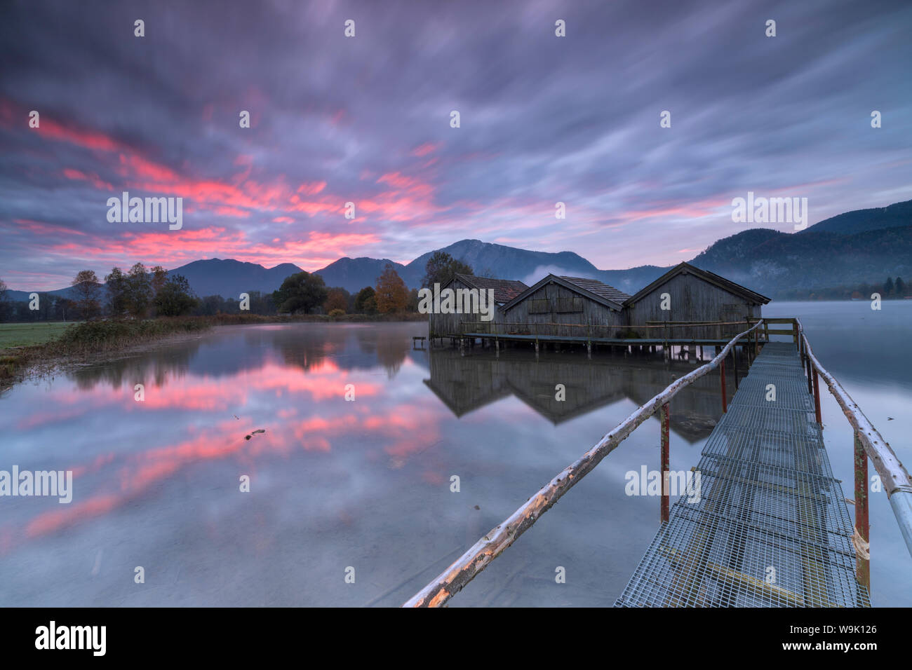 Purple sky at sunset et cabanes de bois se reflètent dans l'eau claire de Kochelsee, Schlehdorf, Bavaria, Germany, Europe Banque D'Images