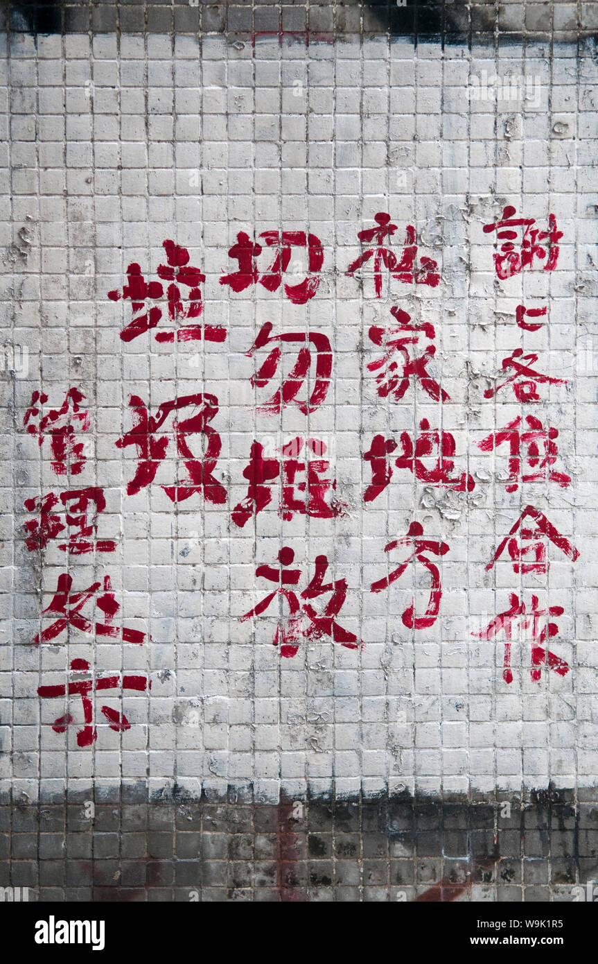 Personnages chinois sur UN mur en carreaux peint en blanc à Kowloon, Hong Kong Banque D'Images