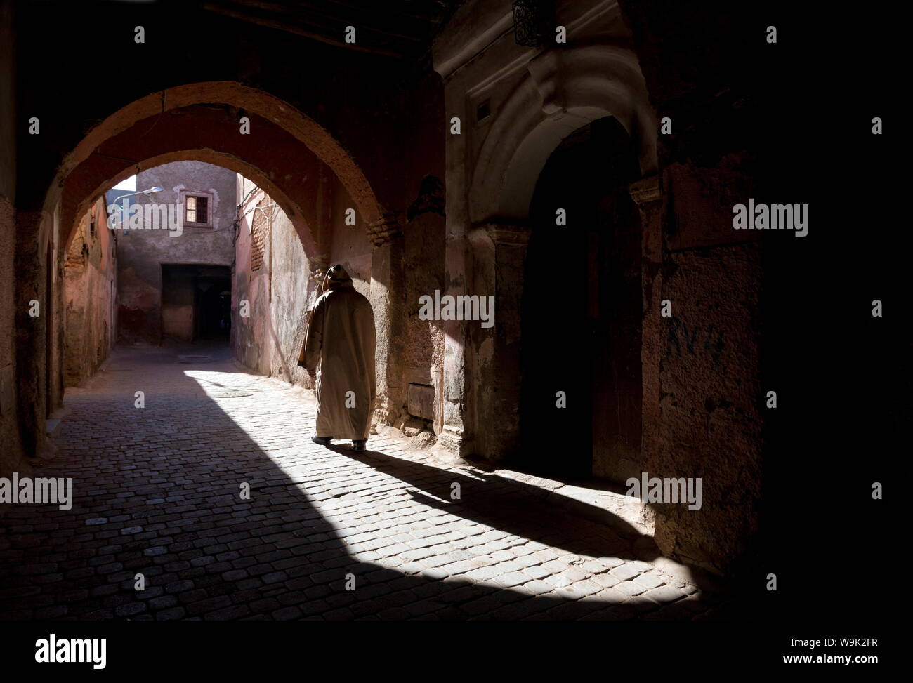 Homme portant une djellaba jette une ombre dans une rue ensoleillée dans la Kasbah, Marrakech, Maroc, Afrique du Nord, Afrique Banque D'Images