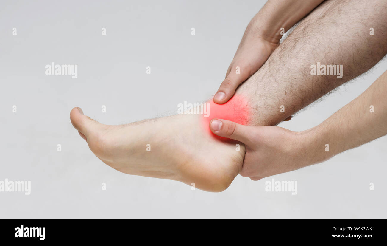 Man main massant sa douleur aux jambes à cause de la cheville tordue Banque D'Images