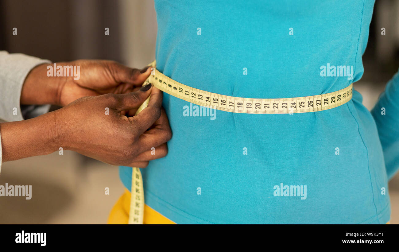 Femme noire mesurant la taille de mains Femme en Design Studio, gros plan Banque D'Images