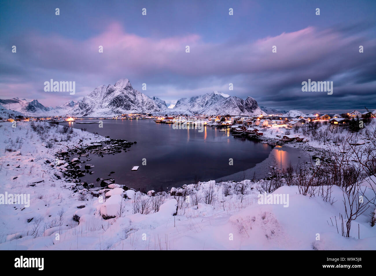Les couleurs de l'aube sur le village de pêcheurs entouré de sommets enneigés et la mer gelée, Reine, Nordland, îles Lofoten, Norvège, de l'Arctique, Scandinavie, Europe Banque D'Images