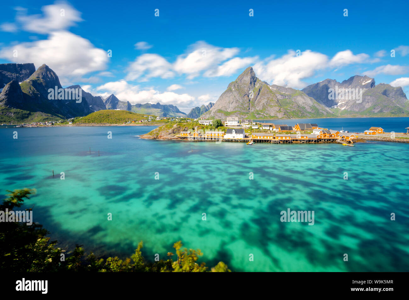 La mer turquoise entoure le typique village de pêcheurs entouré de pics rocheux, Sakrisoy, Reine, Moskenesoya, îles Lofoten, Norvège, Scandinavie Banque D'Images