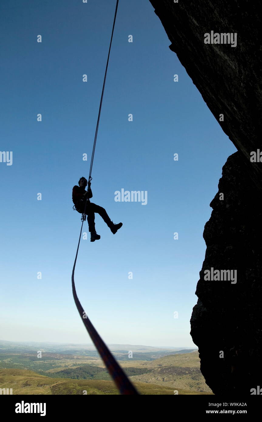 Un grimpeur suspendue fait un rappel d'une falaise abrupte dans l'Ogwen Valley, près de Tryfan et Snowdon, Galles, Royaume-Uni, Europe Banque D'Images