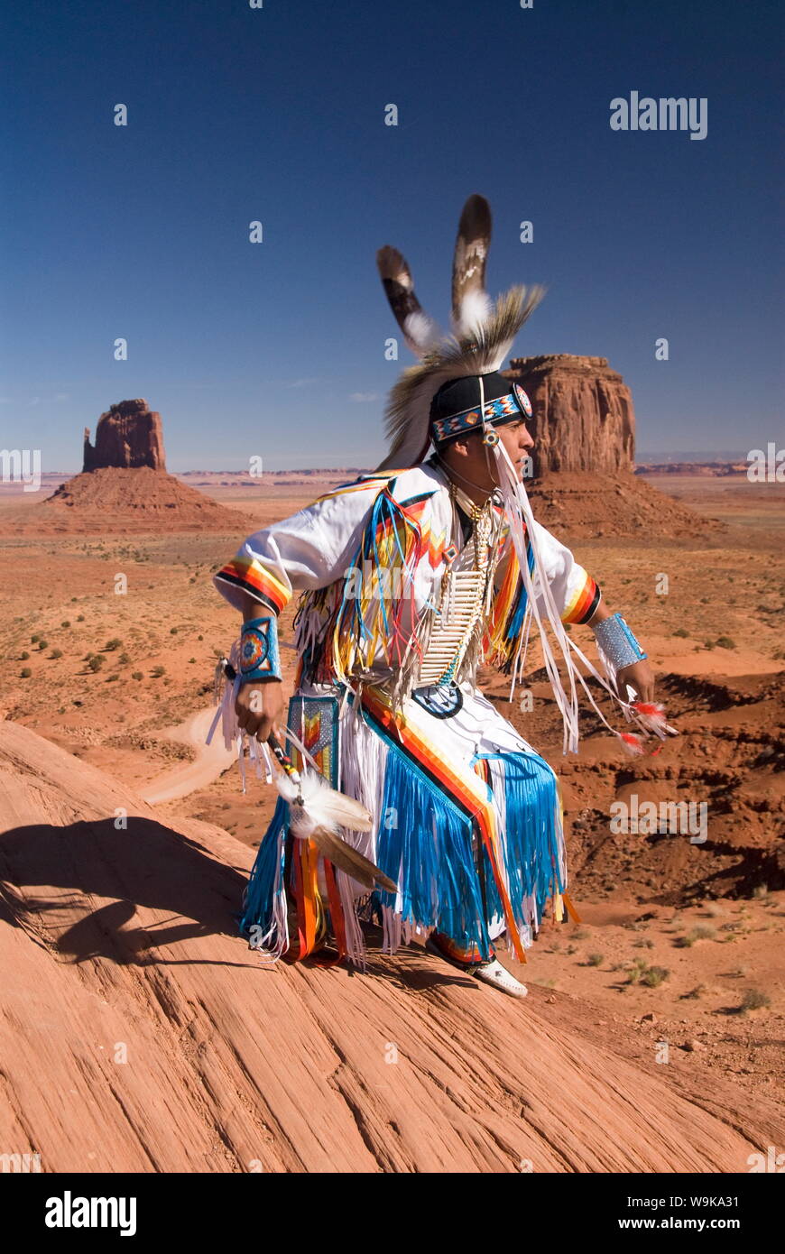 Homme Navajo en costume traditionnel dansant, avec Merrick Butte et East Mitten Butte, Monument Valley Navajo Tribal Park, Utah, USA Banque D'Images