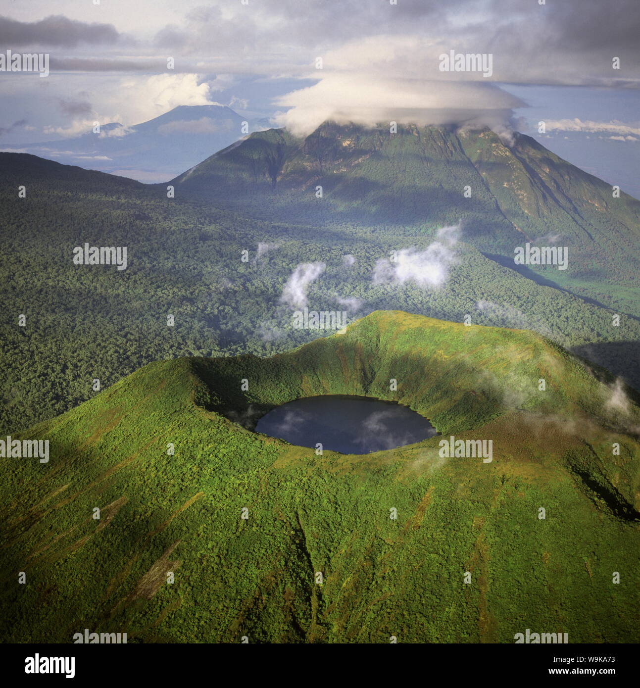 Vue aérienne du mont Visoke (Mount Bisoke) montrant le lac du cratère, avec le Mont Mikeno en arrière-plan, Volcans Virunga, Great Rift Valley Banque D'Images