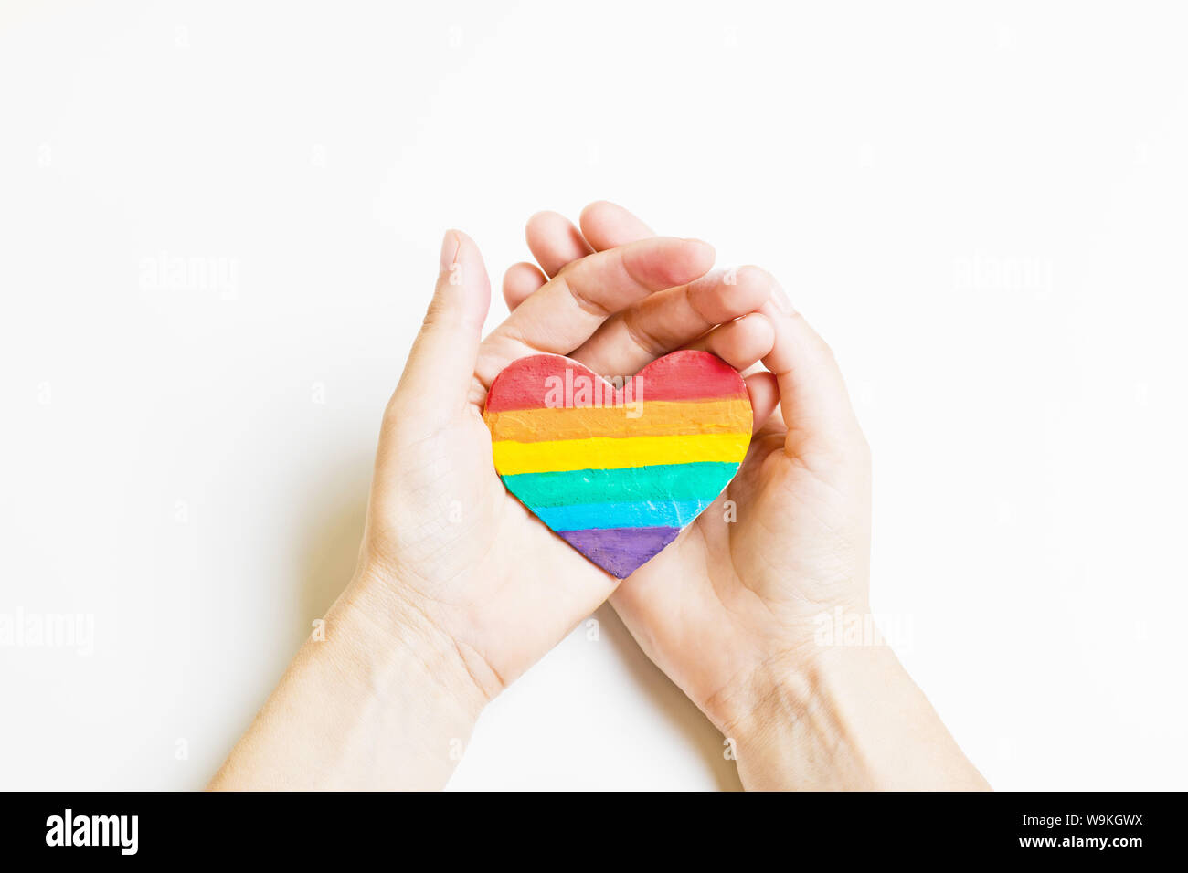 Symbole LGBT dans la main. Coeur de la couleur arc-en-ciel sur un fond blanc Banque D'Images
