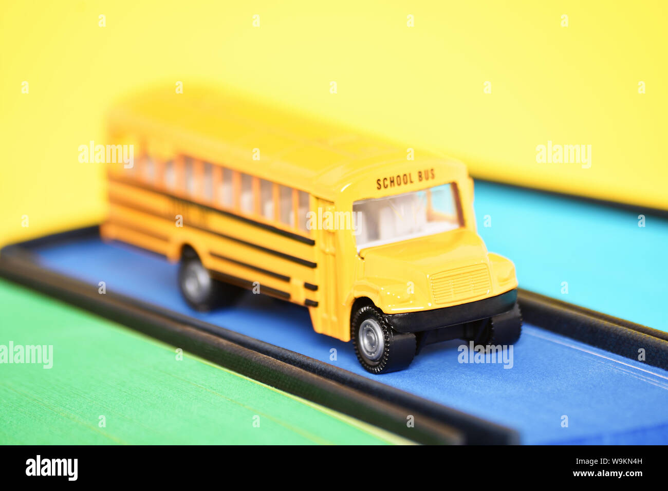 Gros plan d'un autobus scolaire jouets sur le dessus d'un livre avec bords  pulvérisé bleu sur fond jaune Photo Stock - Alamy