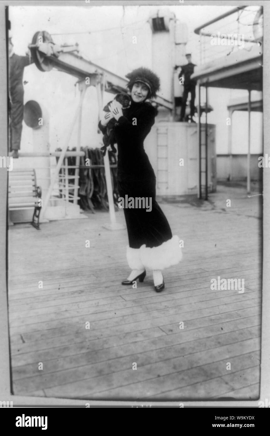 Annette Kellerman, portrait en pied, debout sur le pont du navire, de face, tenant un chien noir (PUG) Banque D'Images