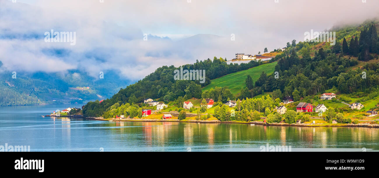 Olden, Norvège, village européen norvégien paysage bannière sur le fjord, montagnes, nuages et colorés des maisons traditionnelles Banque D'Images