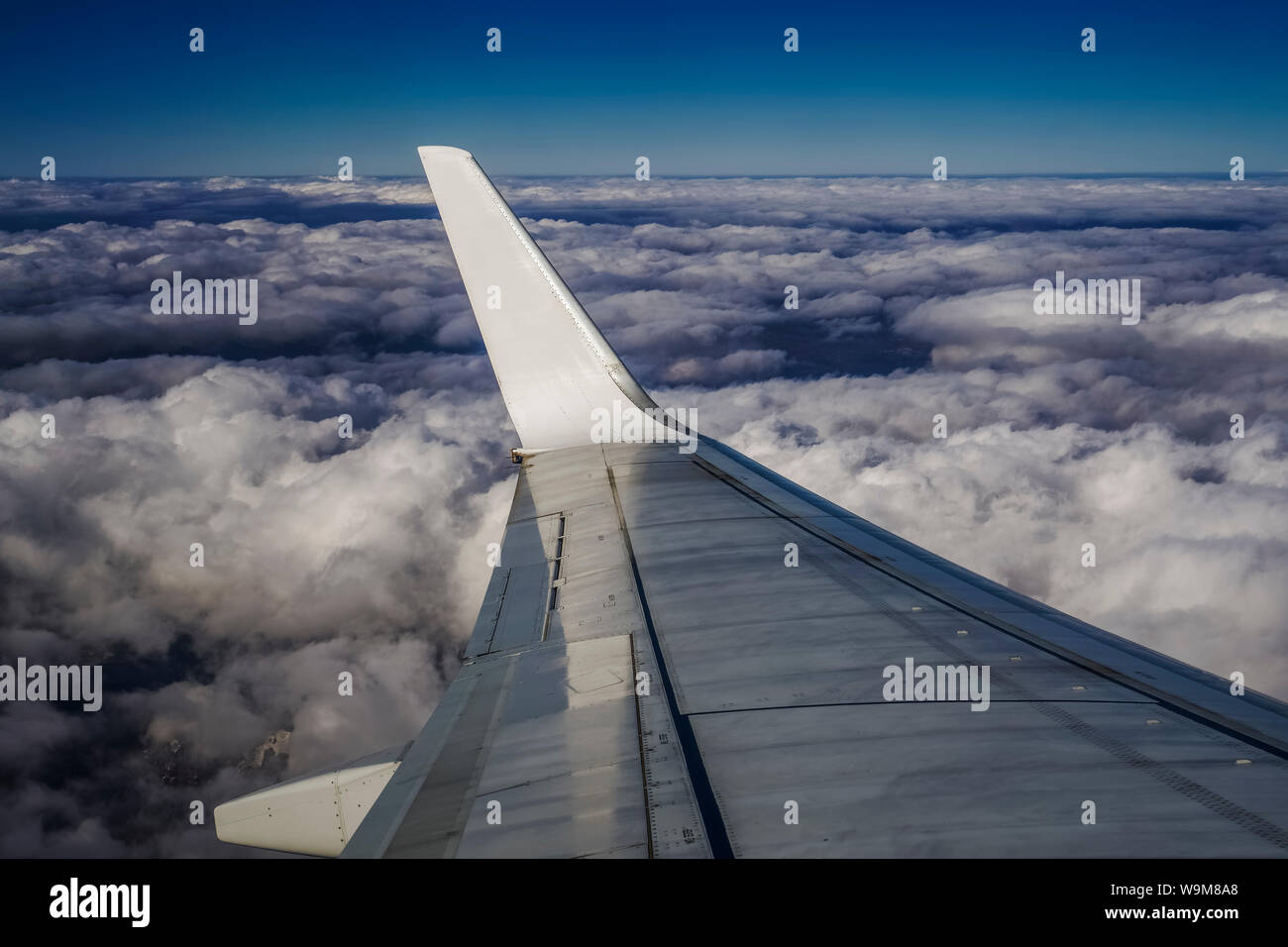 Voir l'aile de la fenêtre de vol à haute altitude au-dessus de l'avion nuages gonflés lit. La vue quotidienne à l'intérieur de la fenêtre d'un avion sans aile métal logo d'opérateur Banque D'Images