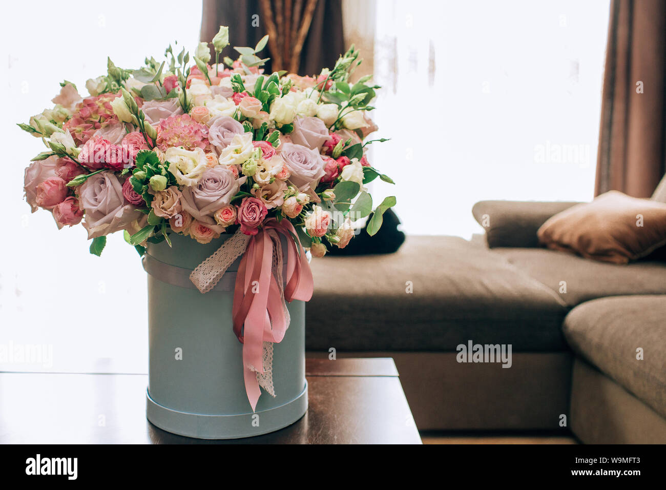 Bouquet de fleurs moderne en bleu boîte ronde sur une table en bois. Bel  arrangement de fleurs dans une boîte à chapeau. Bouquet de fleurs dans la  caisse de tête Photo Stock -