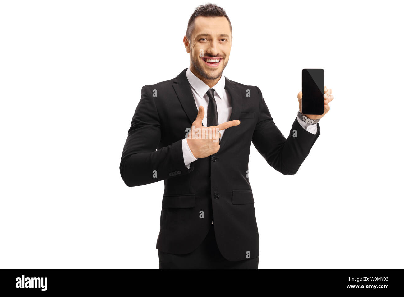 Cheerful young man in a suit holding a mobile phone et en montrant qu'il isolé sur fond blanc Banque D'Images