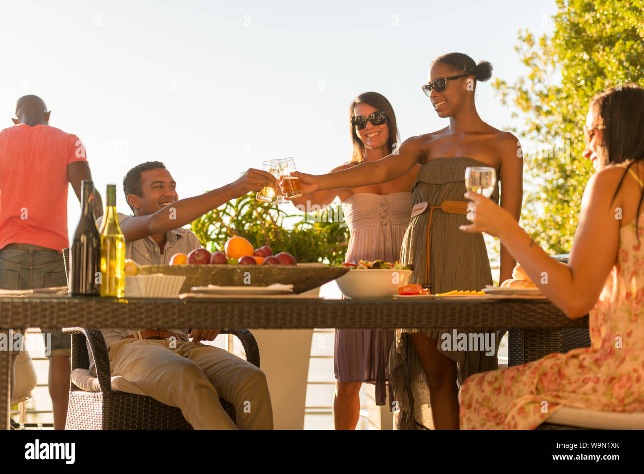 Cinq amis se réunissent pour un dîner barbecue dans le patio à l'extérieur dans la soirée Banque D'Images