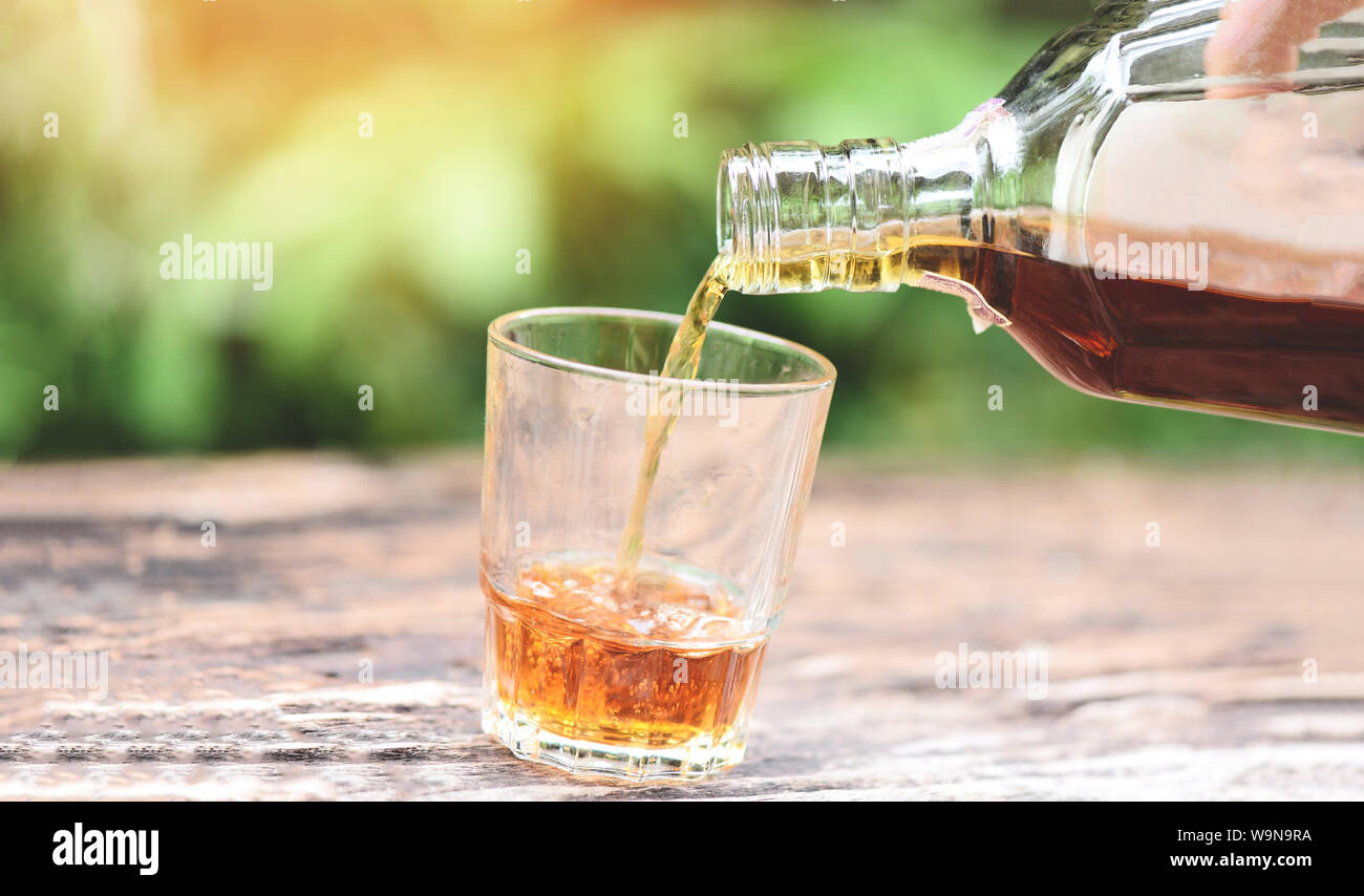 Verser de l'alcool boire du whisky ou du biberon à lunettes sur fond de bois / Pour liquor Banque D'Images