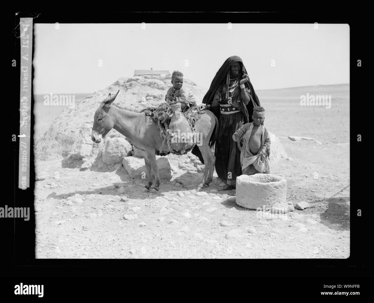 Les Bédouins de Beersheba. Un désert citerne. (Les femmes et les enfants avec un âne chargé avec des pots d'eau) Banque D'Images