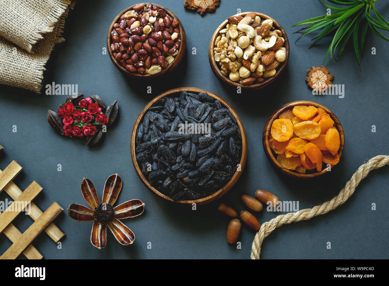 Noix assorties et fruits secs dans des bols en bois sur un fond sombre, idéal pour grignoter en bonne santé. Banque D'Images