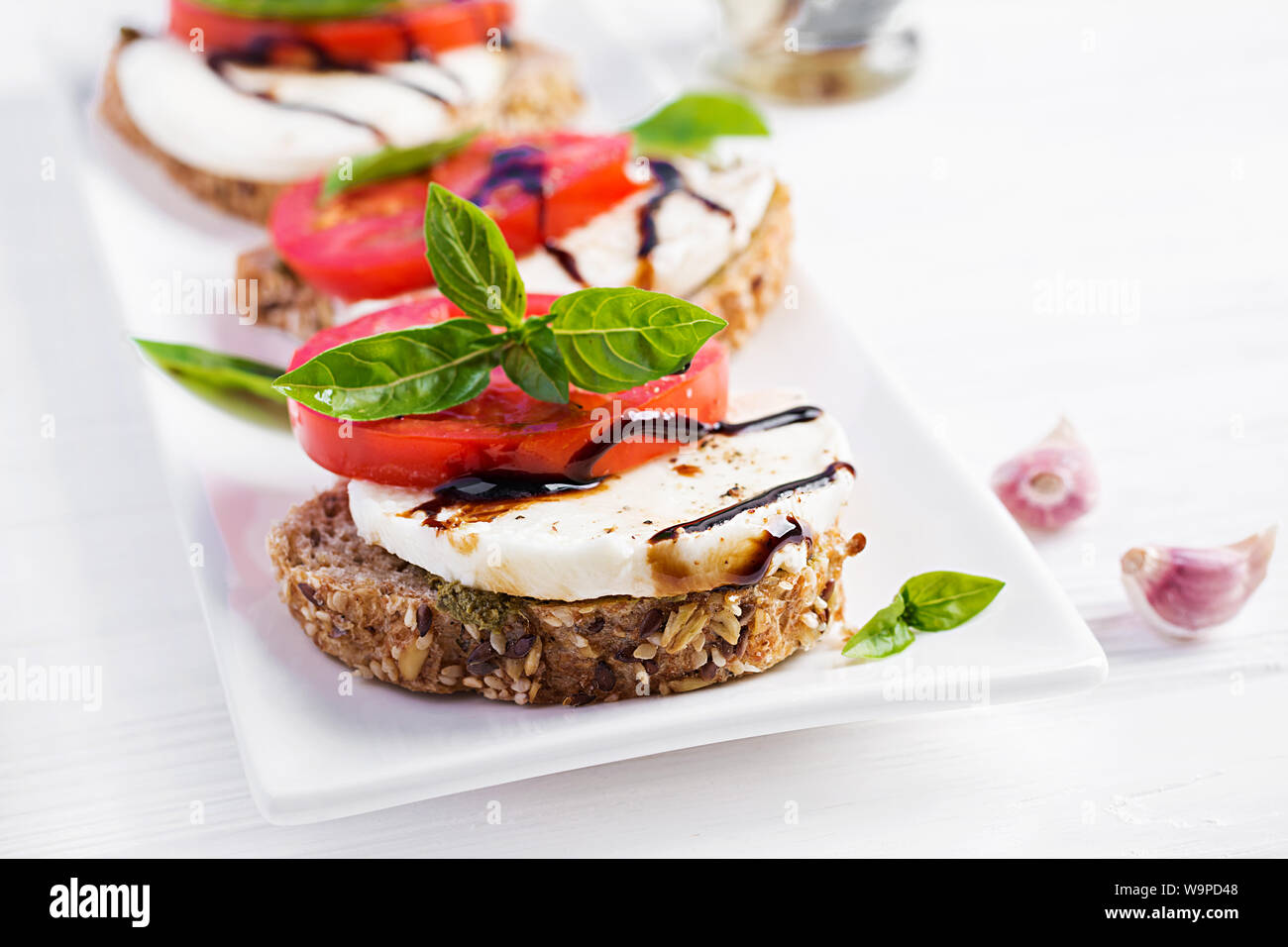 Des sandwichs avec de la mozzarella, tomates et pain de seigle sur table en bois blanc. Banque D'Images