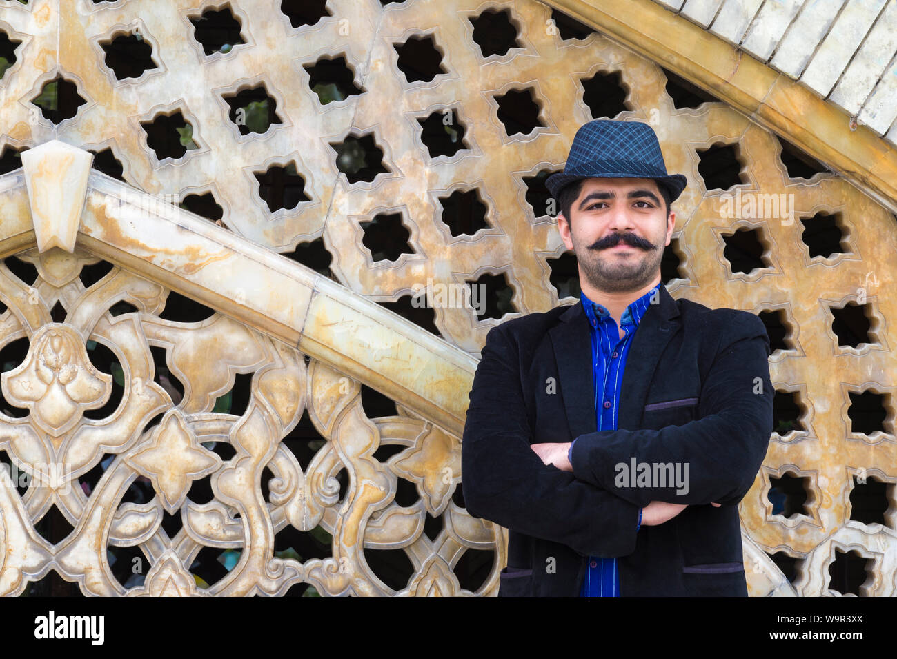 Iranien contre un mur sculpté, le Golestan Palace, Téhéran, République islamique d'Iran Banque D'Images