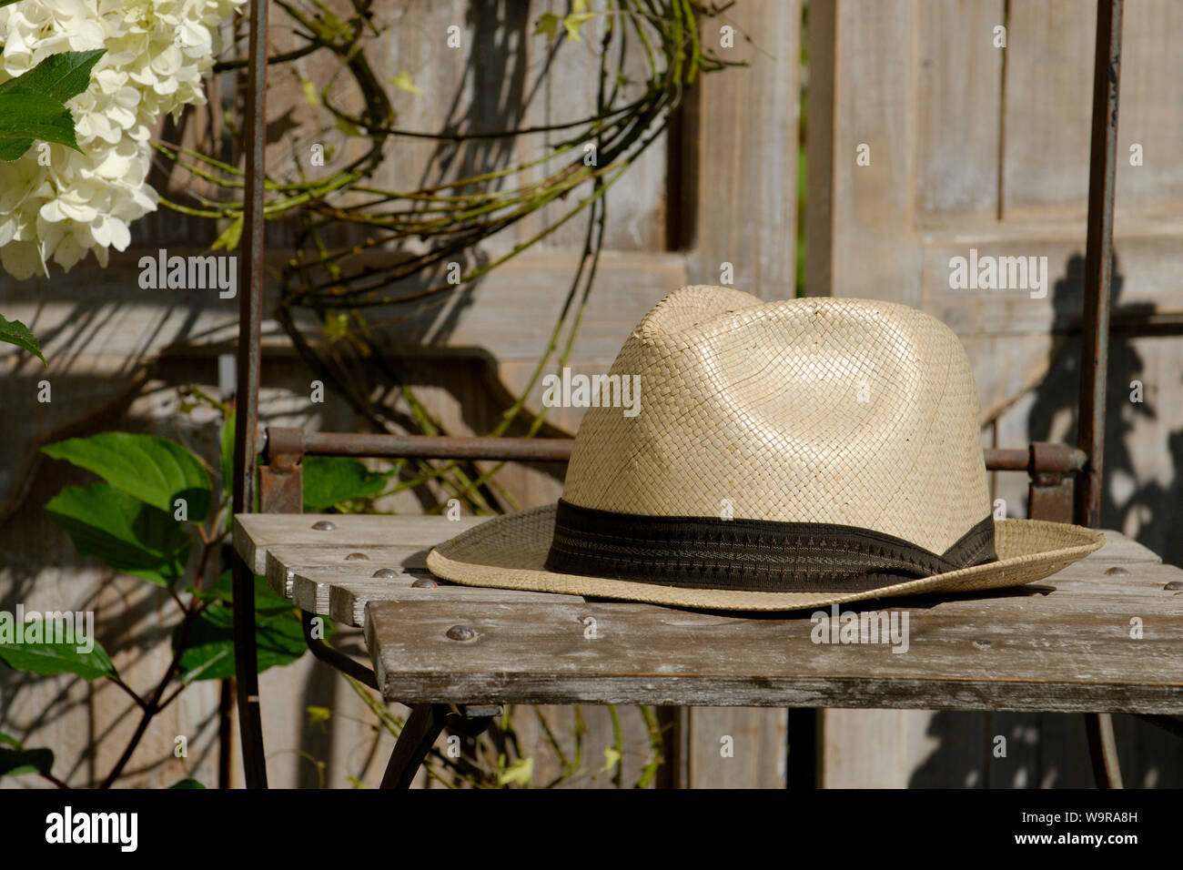 Chapeau de paille sur chaise de jardin Photo Stock - Alamy