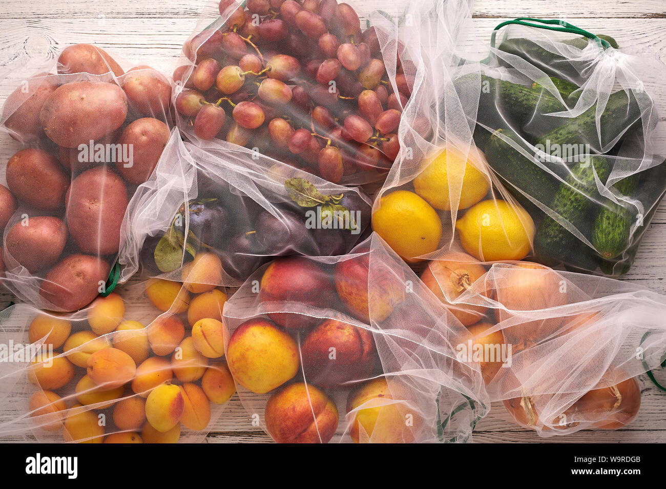 Fruits et légumes dans des sacs réutilisables eco à fond de bois blanc. Sacs recyclés au lieu de sacs en plastique. Articles de plastique. Vue supérieure mise à plat Banque D'Images