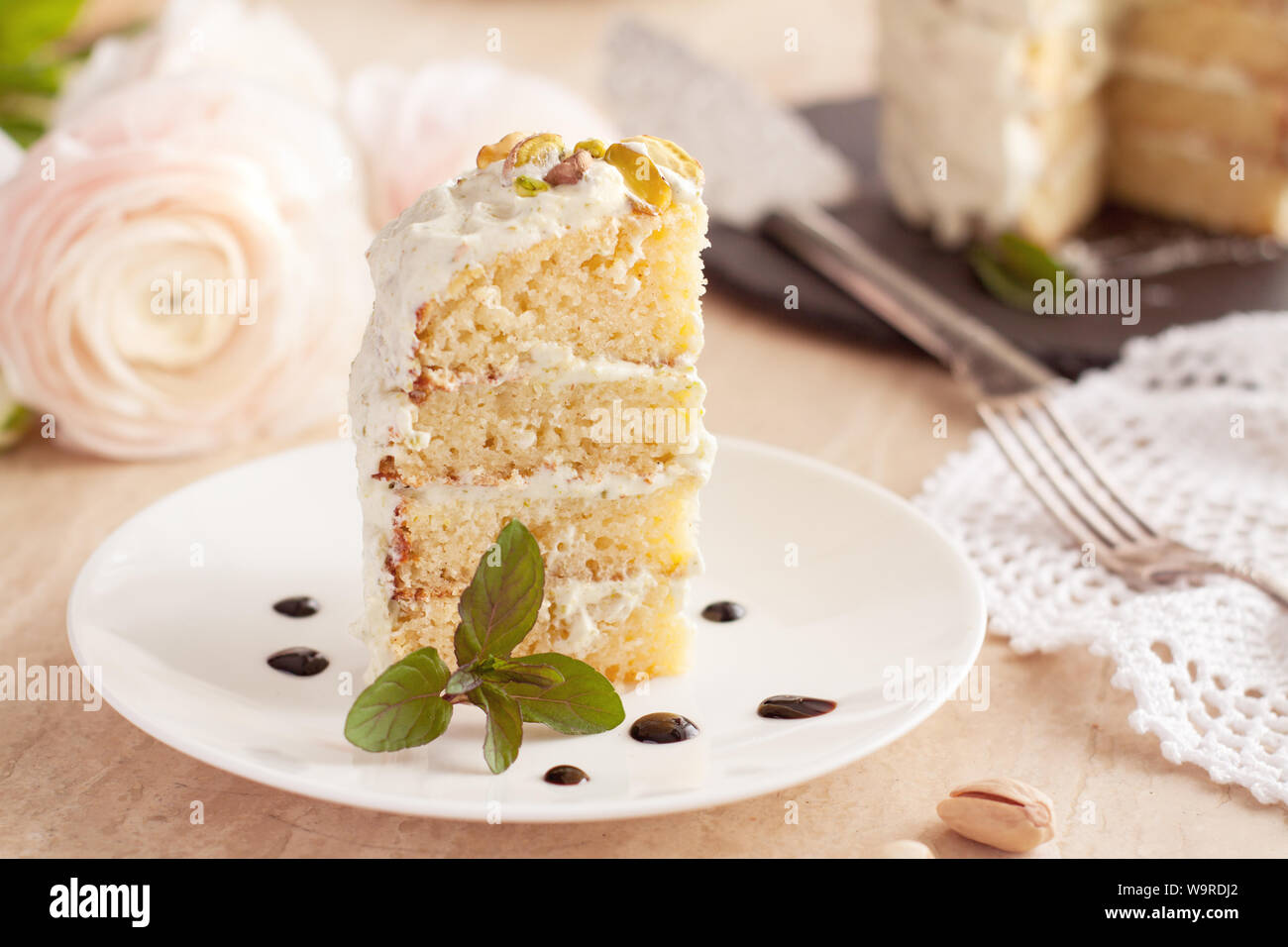 Pièce d'Airy pistaches gâteau avec du glaçage décoré de feuilles de menthe fraîche Banque D'Images