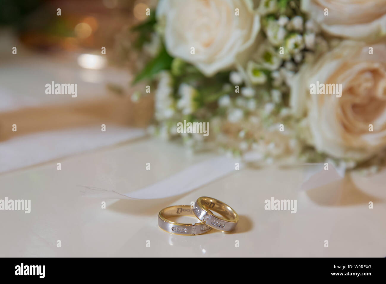 Fleur de mariage blanc élégant anneaux situés à l'avant du bouquet de mariage . Plates-formes de mariage devant un bouquet de mariage. Profondeur de champ Banque D'Images