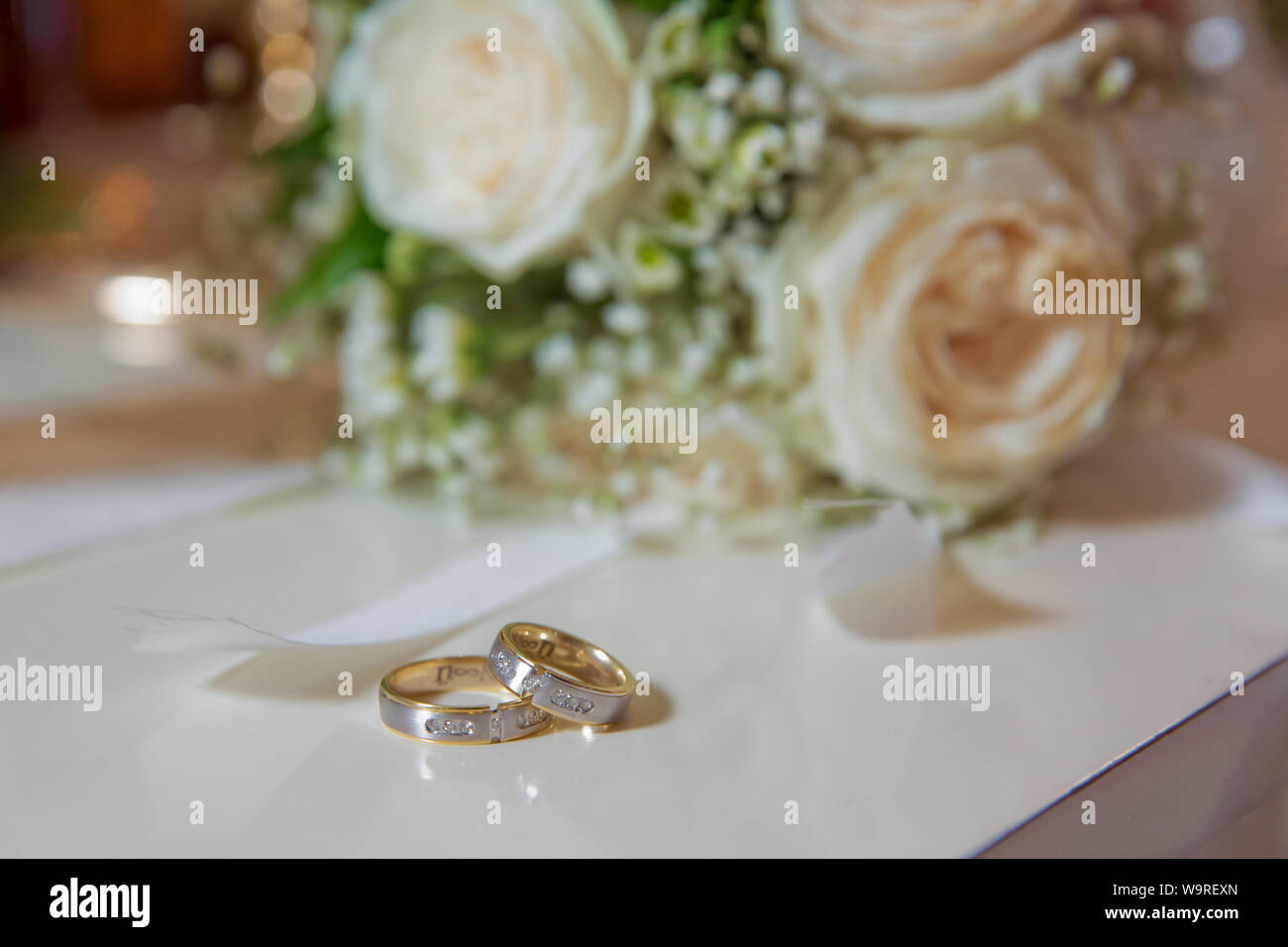 Fleur de mariage blanc élégant anneaux situés à l'avant du bouquet de mariage . Plates-formes de mariage devant un bouquet de mariage. Profondeur de champ Banque D'Images