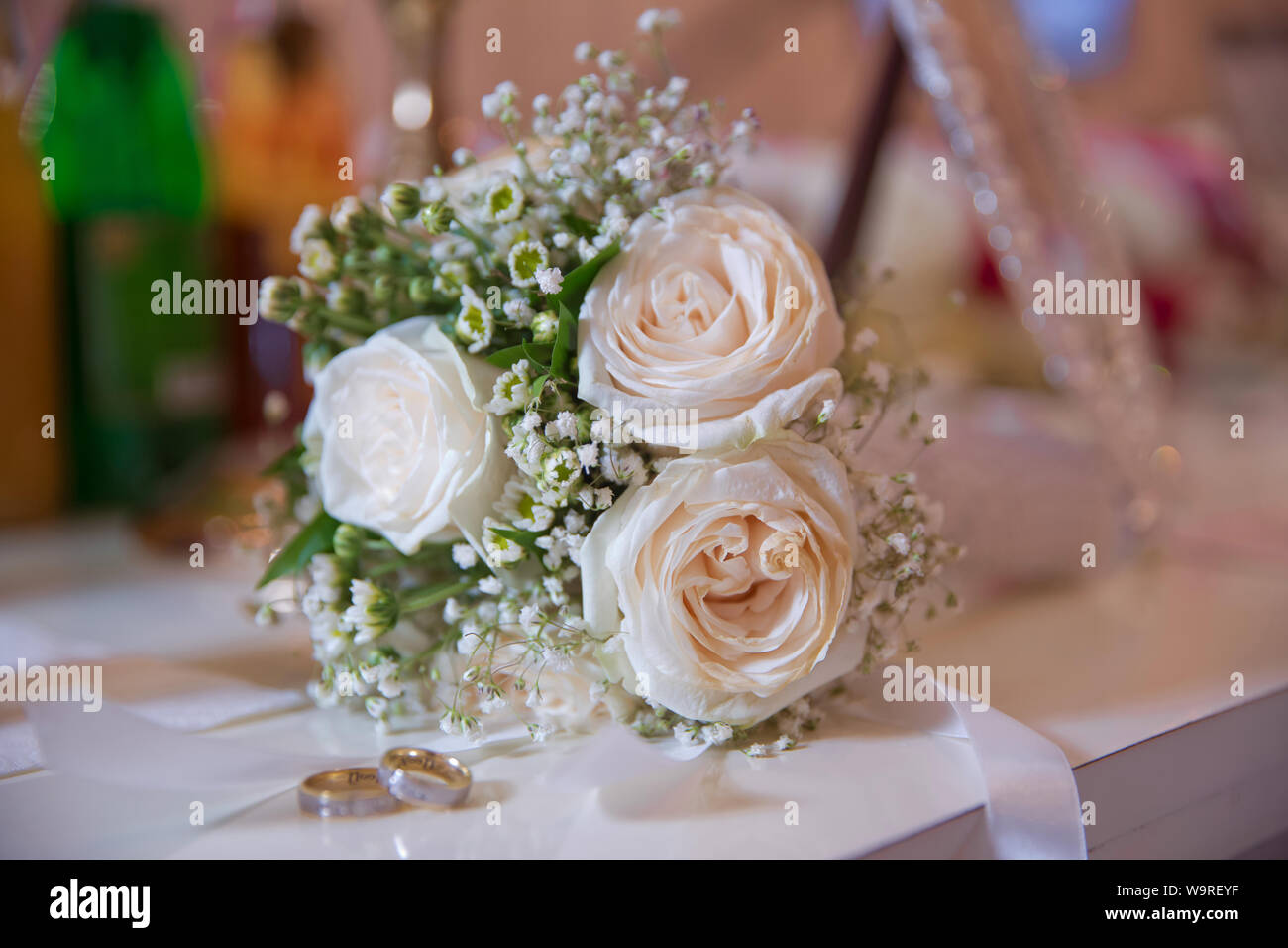 Fleur de mariage blanc élégant anneaux situés à l'avant du bouquet de mariage . Plates-formes de mariage devant un bouquet de mariage. Profondeur de champ Banque D'Images