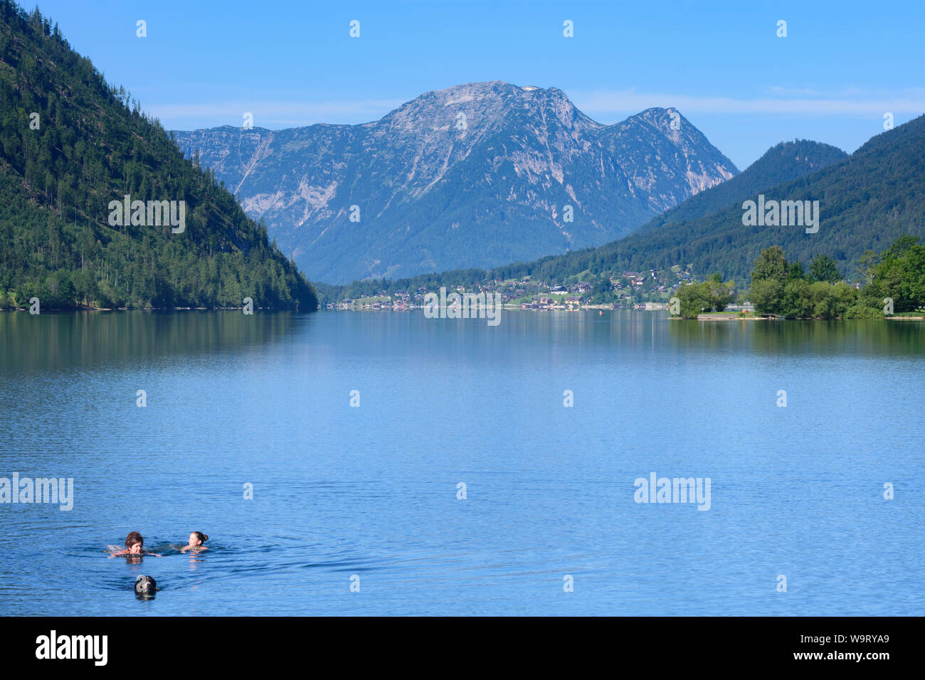 Grundlsee : lac Grundlsee extrémité orientale à Gößl, vue à l'ouest de village de montagne et Grundlsee Zinken, nageur, baigneur, natation chien dans Ausseerland-Sal Banque D'Images