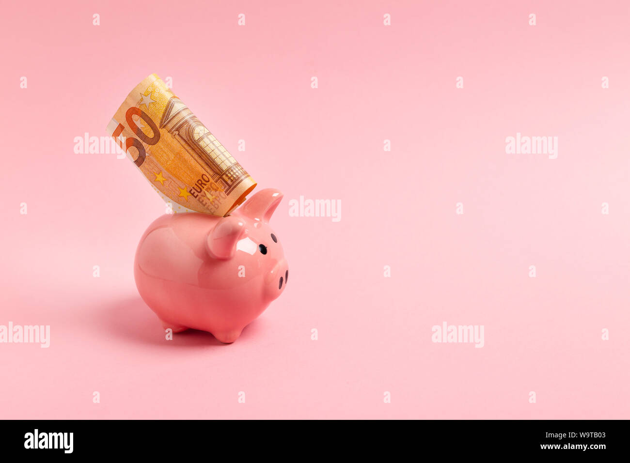 Pink piggy bank avec cinquante euros sur un fond rose. Banque D'Images
