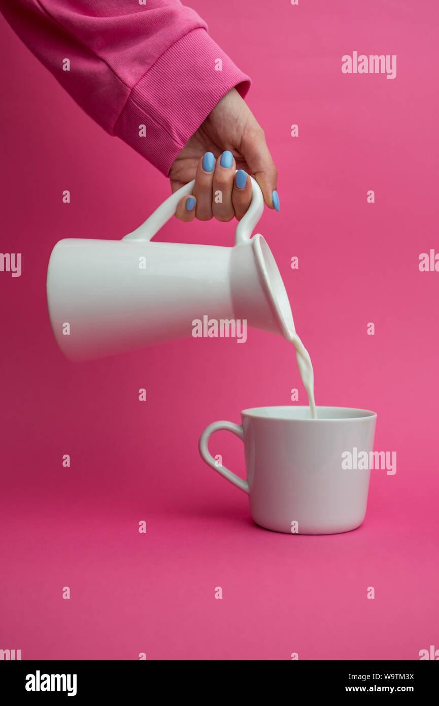 Woman pouring un pichet de lait dans une tasse Banque D'Images