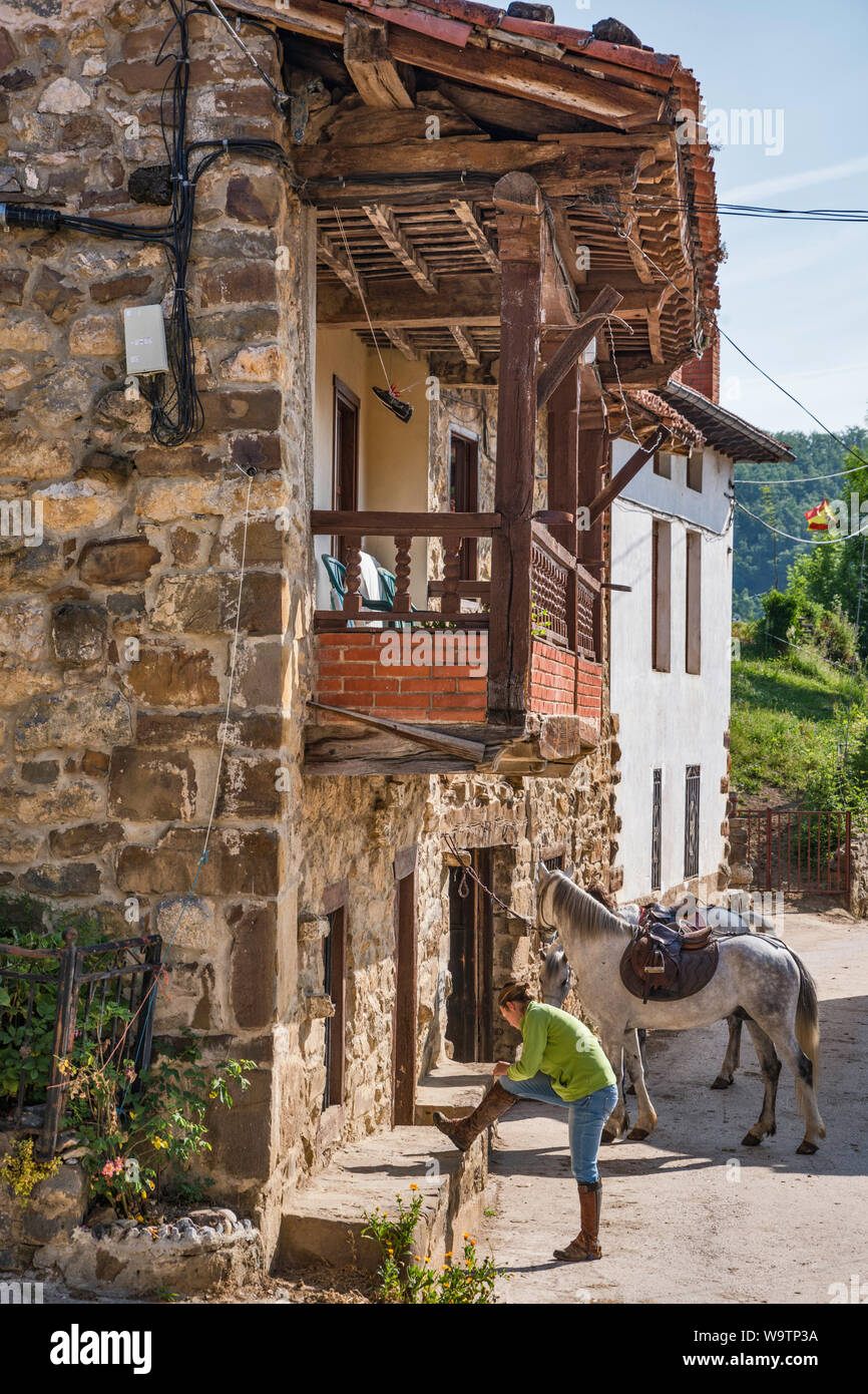 Jeune femme se préparant à monter à cheval, village de Pembes, Macizo Central (Macizo Los Urrieles) dans les Picos de Europa, Cantabria, ESPAGNE Banque D'Images