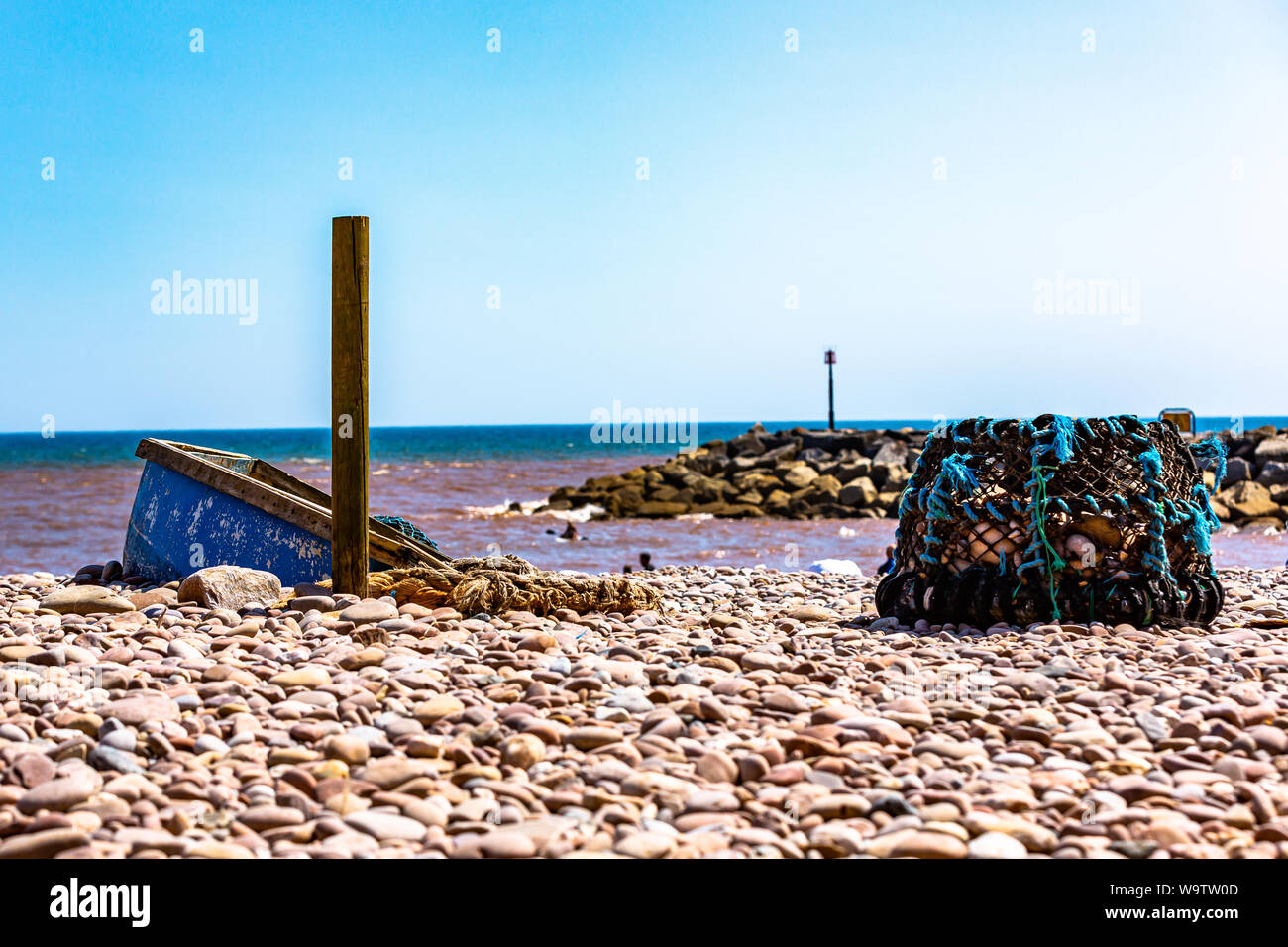 Un vieux bateau de pêche et des filets abandonnés sur une plage de galets de Sidmouth. Banque D'Images
