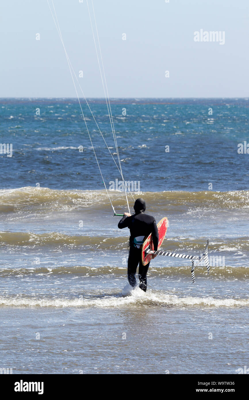 Kite Surfer Carrying Hydofoil board sur le point d'entrer dans l'océan Banque D'Images