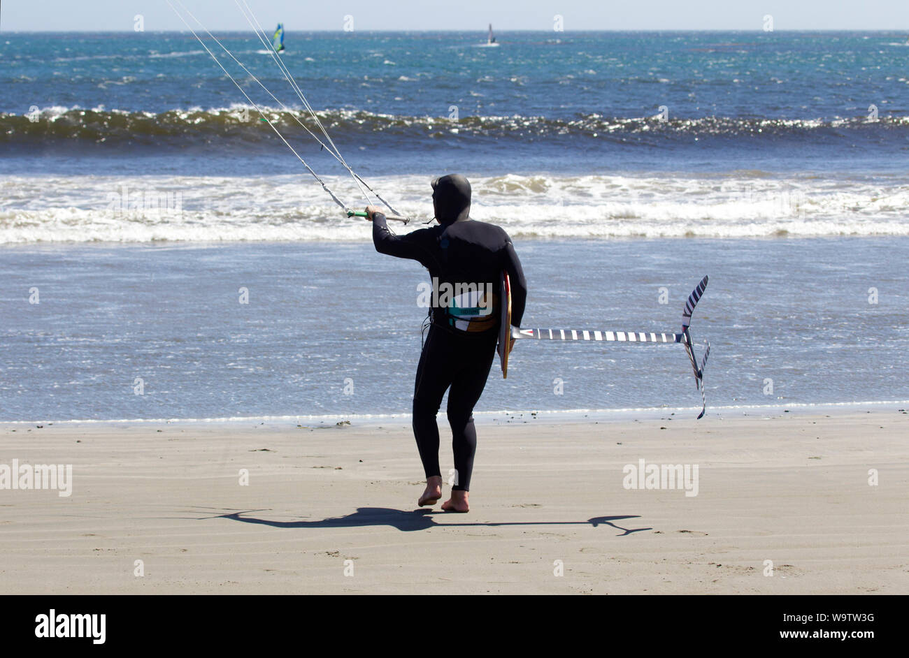 Kite Surfer Carrying Hydofoil board sur le point d'entrer dans l'océan Banque D'Images