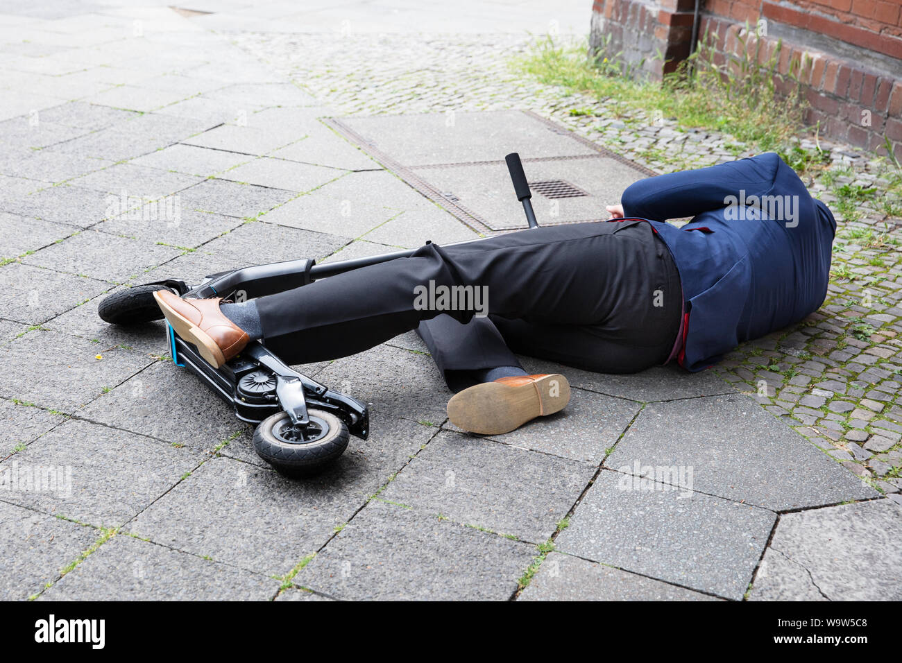 Homme inconscient allongé sur le béton rue après accident avec un Scooter électrique Banque D'Images