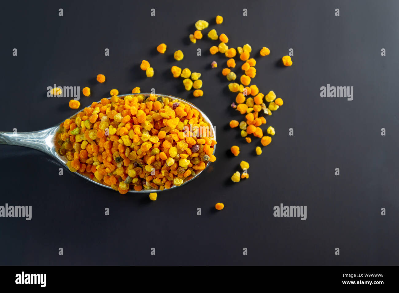Les granules de pollen d'abeille dans la cuillère sur le fond sombre. Banque D'Images