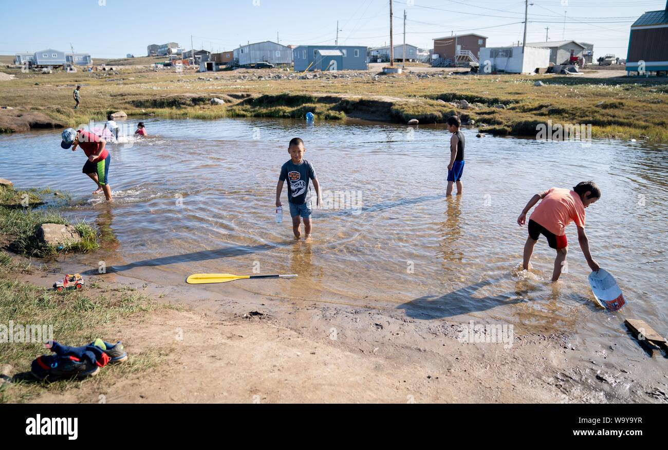 Pond Inlet, Canada. Août 15, 2019. Les enfants Inuit jouer à une température ambiante de 12 degrés dans un petit lac dans la ville de Pond Inlet, dans l'Arctique canadien. Le petit village Inuit avec seulement 1 300 habitants vont faire face aux conséquences du changement climatique, qui n'est nulle part plus visible que dans l'Arctique. Le réchauffement climatique ici est deux à trois fois plus forte que dans d'autres régions du monde. Credit : Kay Nietfeld/dpa/Alamy Live News Banque D'Images