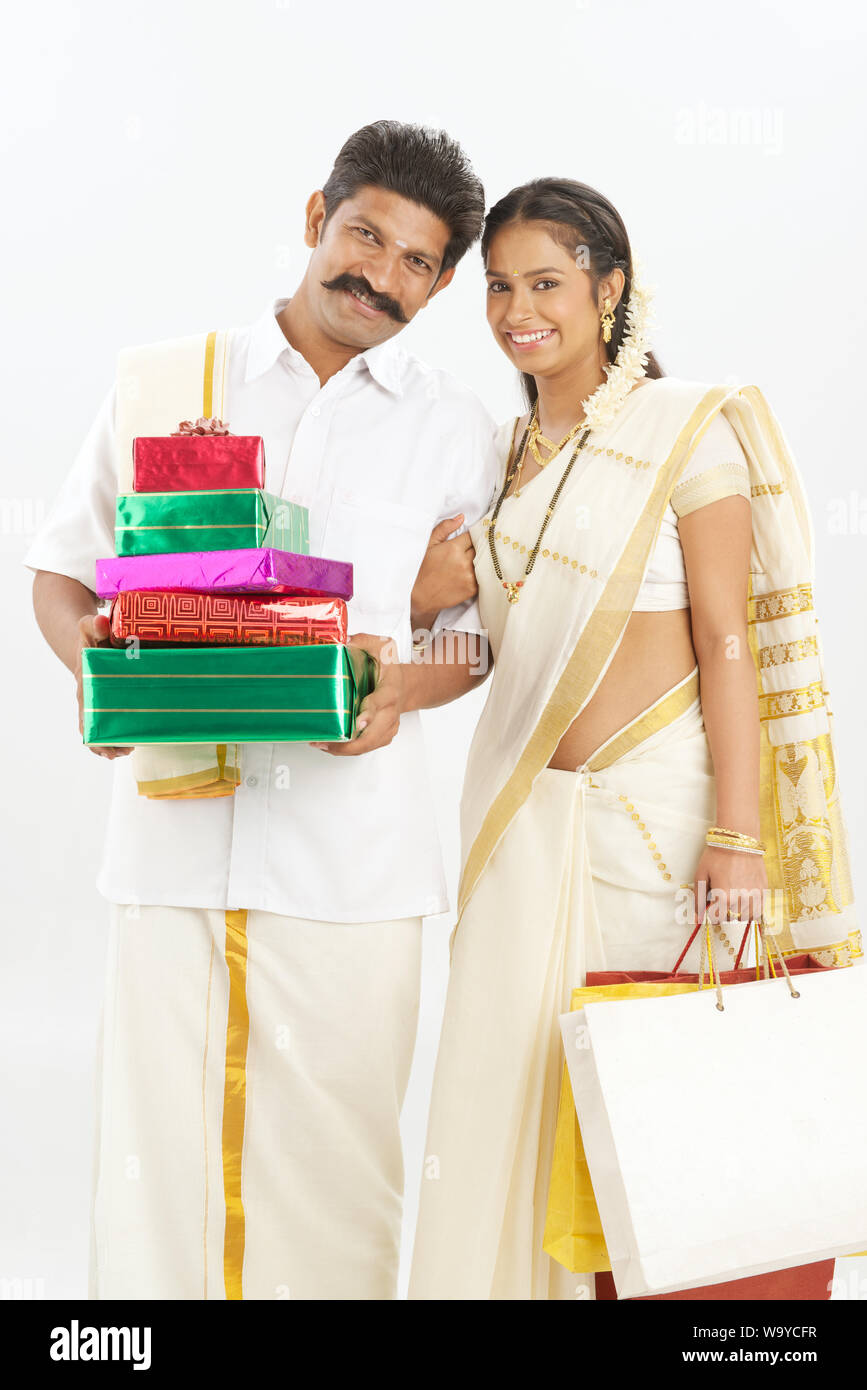South Indian couple holding gift boxes with shopping bags Banque D'Images