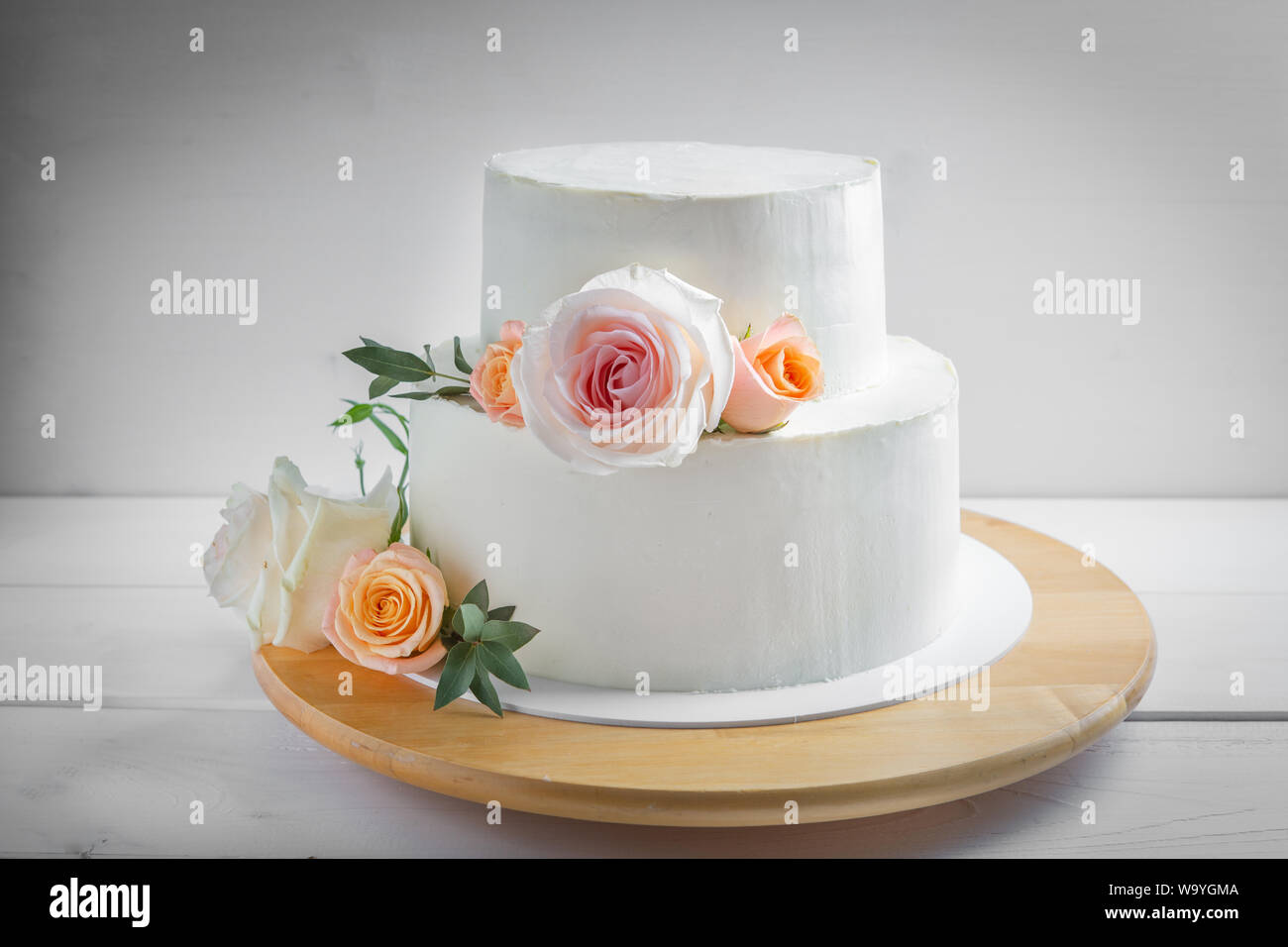 Mariage Blanc Gateau A Deux Etages Decorees De Fleurs Avec Des Feuilles Vertes Dans Un Style Rustique Photo Stock Alamy