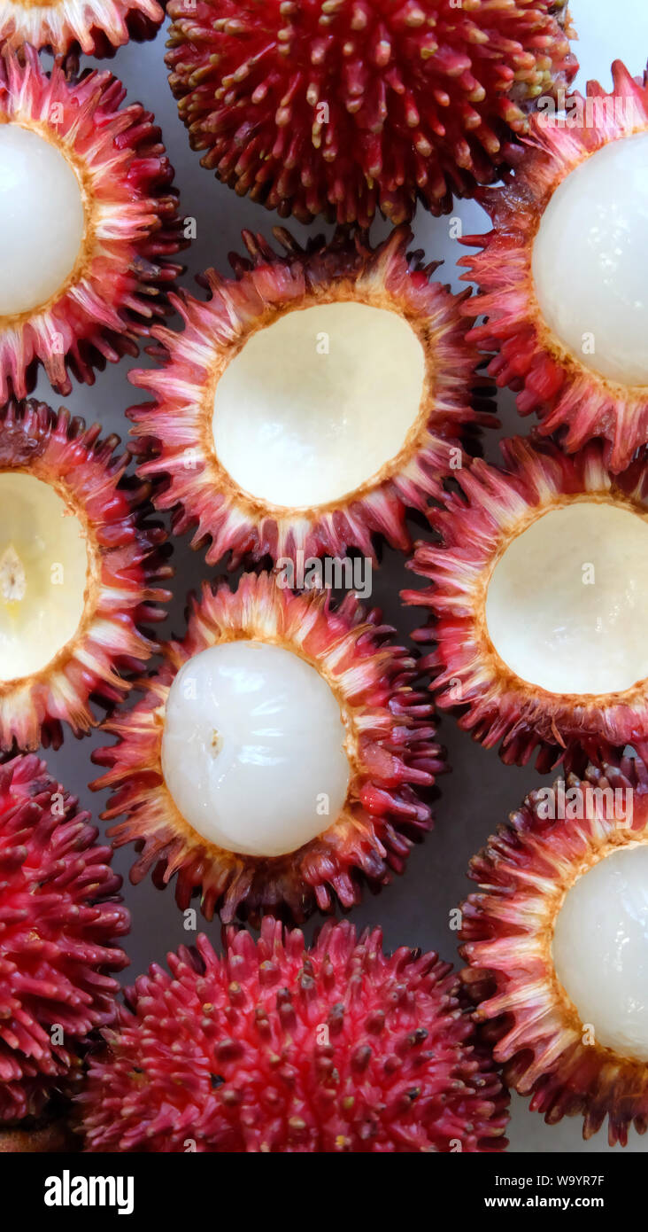 Peau extérieure et une chair blanche pulasan fruits. Vue d'en haut. Nom scientifique Nephelium ramboutan-pulasan akea, est un fruit tropical rouge qui est étroitement liée Banque D'Images