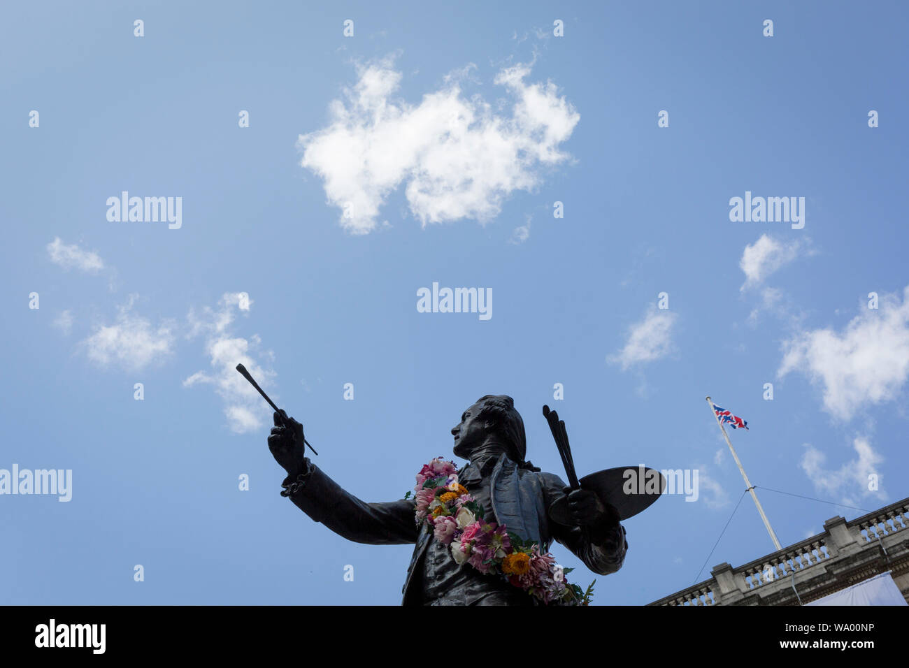 Comme un jeu de mots visuel, la statue de Sir Joshua Reynolds peint seeminly nuages dans le ciel bleu de l'extérieur de l'Académie Royale de Piccadilly au cours de l'exposition d'été, le 13 août 2019, à Londres, en Angleterre. C'est une nouvelle équipe de l'original qui a été présenté pour la première fois en dehors de la RA en 1904 et est une allégorie de l'humain a besoin de nouveaux défis, de notre instinct de toujours être l'horizon et l'avenir. La statue de Sir Joshua se trouve dans le 'côté cour' Annenberg de Burlington House. Banque D'Images