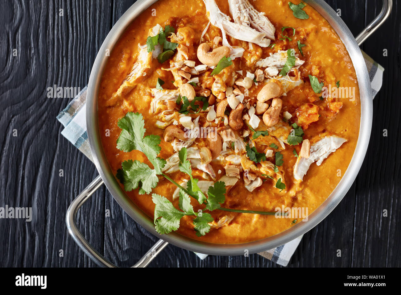 Crémeux de lentilles rouges, les carottes, les pommes et le lait de coco la soupe avec de la viande de poulet dans une casserole en métal sur une table en bois noir, vue de dessus, flatlay, clo Banque D'Images