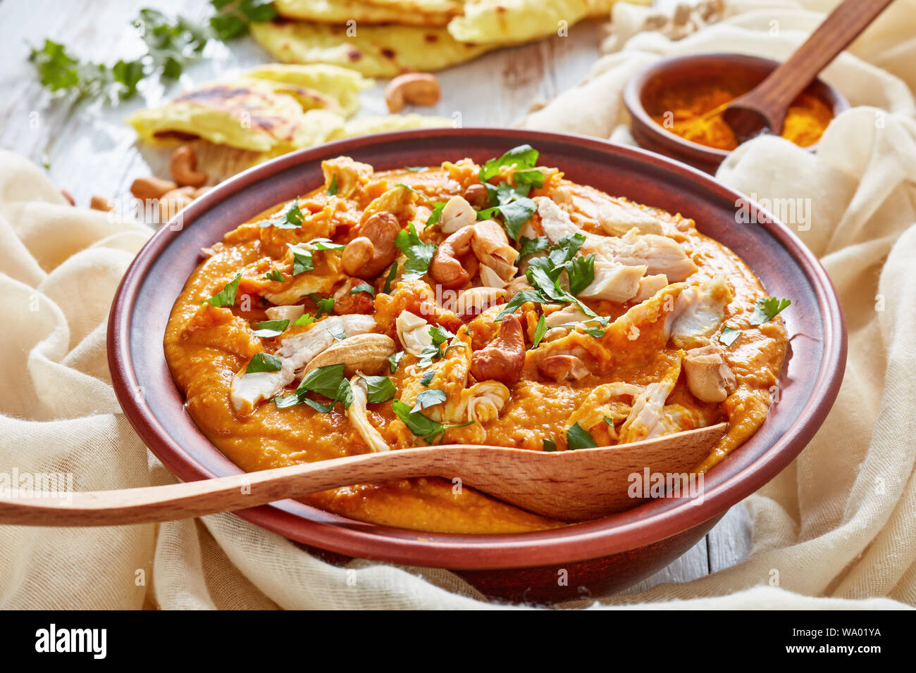 Soupe Mulligatawny avec la viande de poulet et le lait de coco saupoudré de cajou frits dans un bol avec chapati sur une table en bois blanc, Indien et anglais cu Banque D'Images