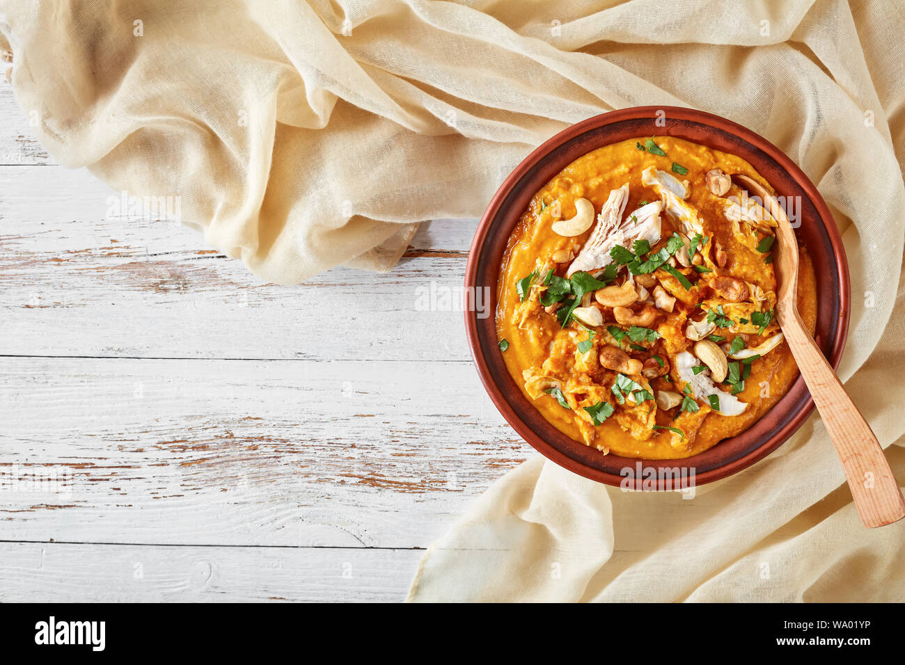 Soupe Mulligatawny avec la viande de poulet et le lait de coco saupoudré de cajou frits dans un bol sur une table en bois blanc avec un chiffon, Indien et anglais cuis Banque D'Images