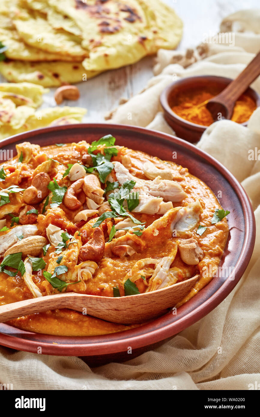 Soupe Mulligatawny avec la viande de poulet et le lait de coco saupoudré de cajou frits dans un bol avec chapati sur une table en bois blanc, Indien et anglais cu Banque D'Images