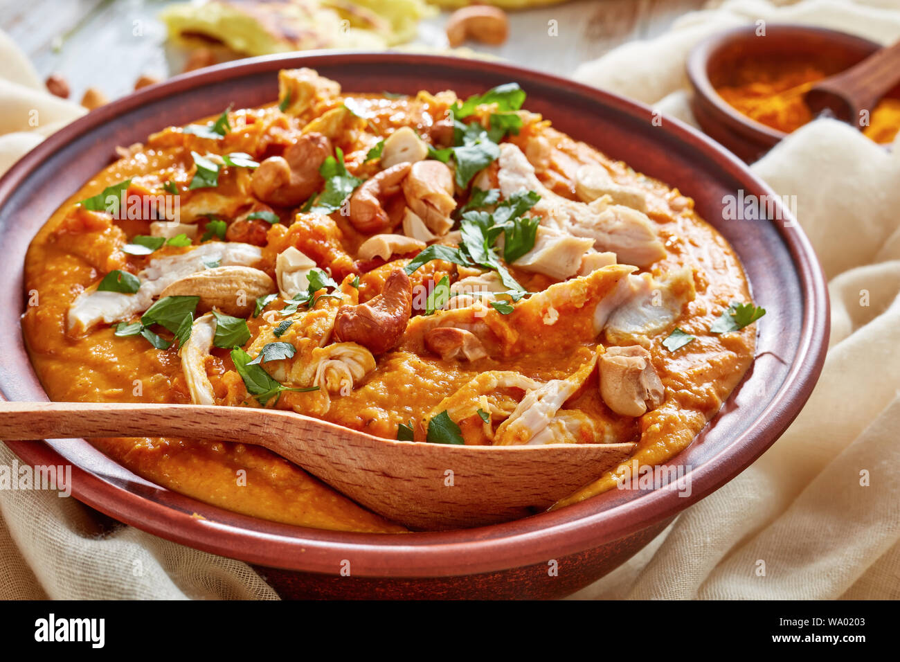 Soupe Mulligatawny avec la viande de poulet et le lait de coco saupoudré de cajou frits dans un bol avec chapati sur une table en bois blanc, Indien et anglais cu Banque D'Images